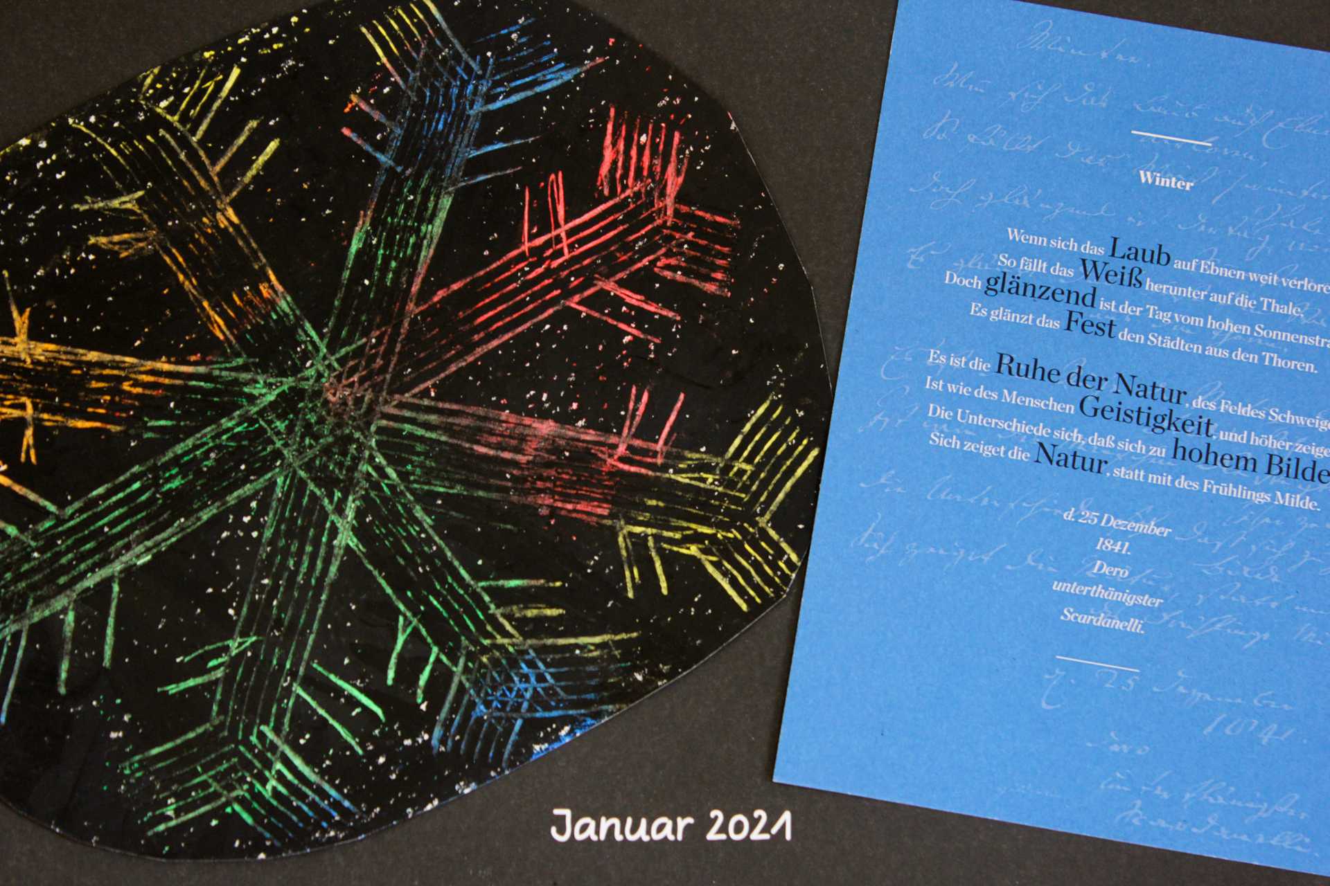 Auf einem Kalenderblatt mit dem Titel Januar ist eine gemalte Schneeflocke neben einer blauen Postkarte mit Hölderlins Gedicht der Winter aufgeklebt