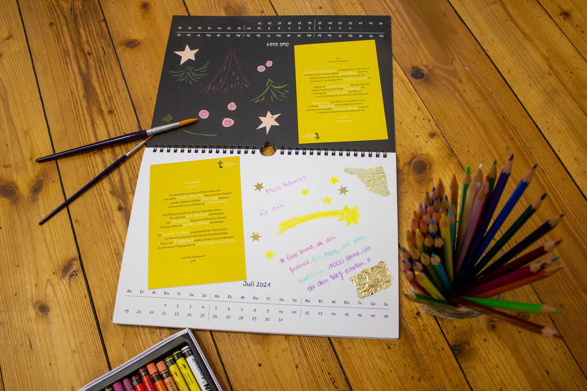 Beide Kalenderseiten liegen auf einem Holztisch nebeneinander