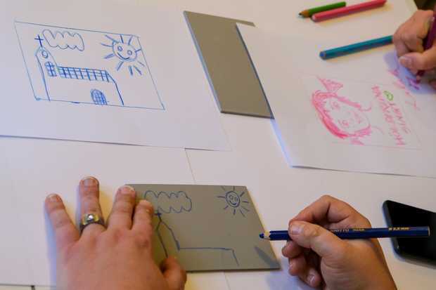 Jemand zeichnet den Umriss einer Linolplatte auf ein Papier.