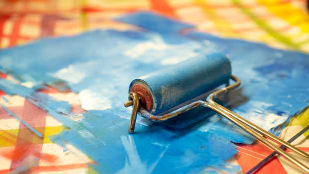 Eine blau-weiß gefärbte Glasplatte. Jemand fährt mit einer blauen Farbwalze darüber.