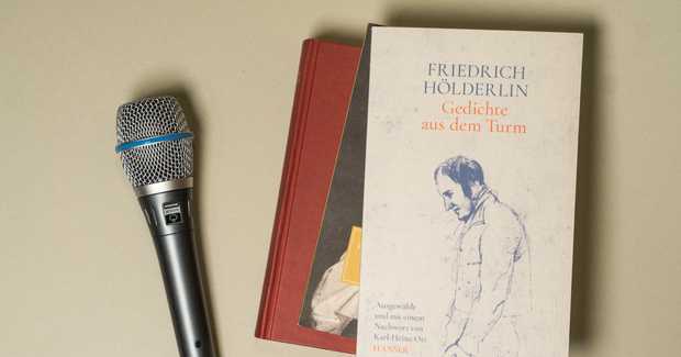 Ein Mikrofon neben einem Stapel mit Büchern.