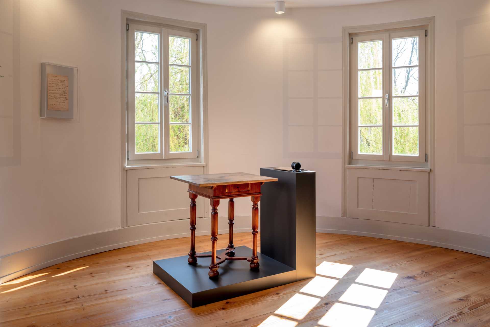 Il y a un petit bureau au milieu de la pièce. Le soleil brille à travers les fenêtres sur les vieux parquet.