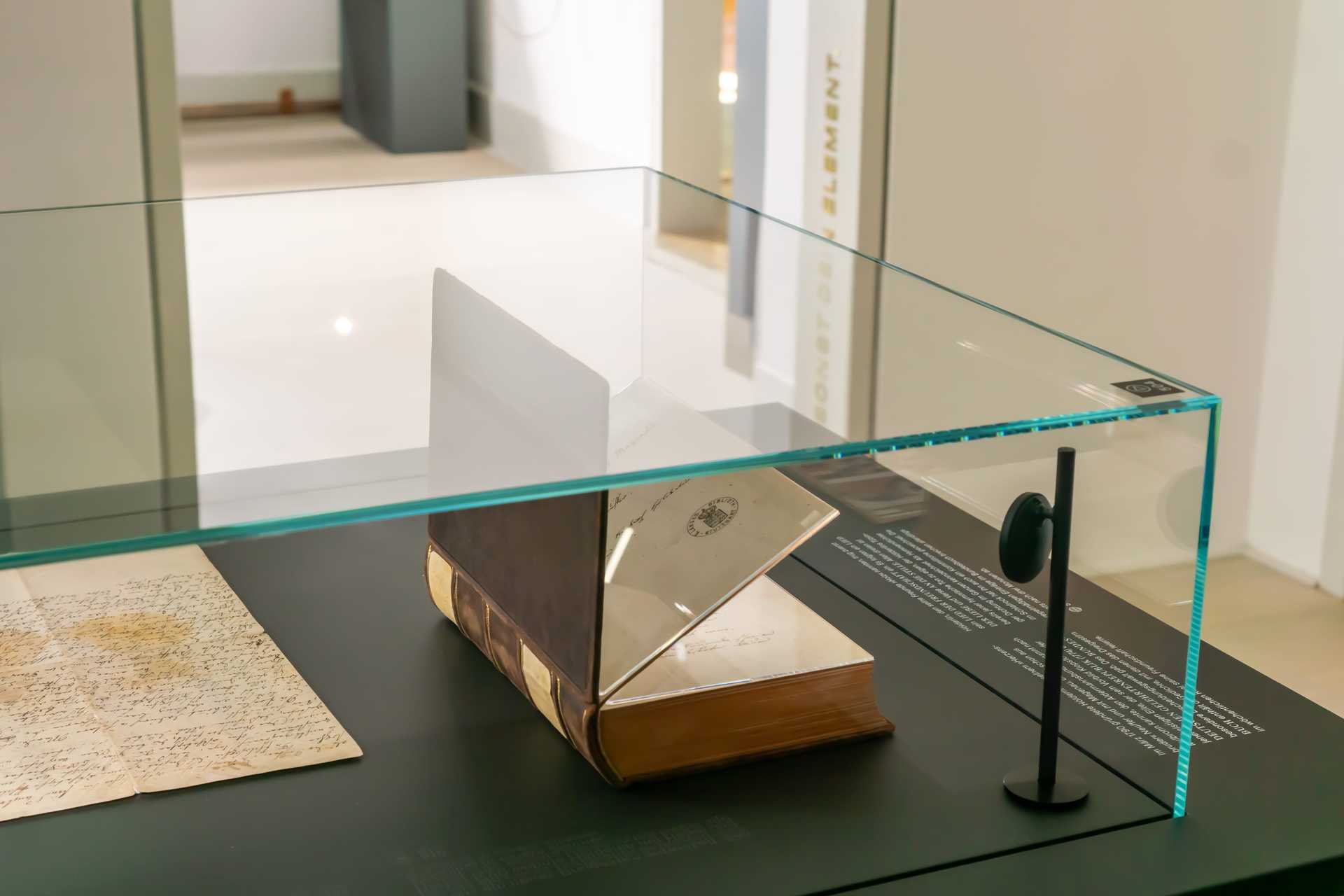 Dunkle Tischvitrine mit aufgeschlagenem Buch