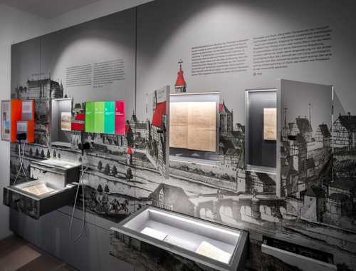 Bild des Raumes Tübinger Hoffnungen im ersten Stock des Turms. An der Wand eine graue Vitrine mit historischer Stadtansicht