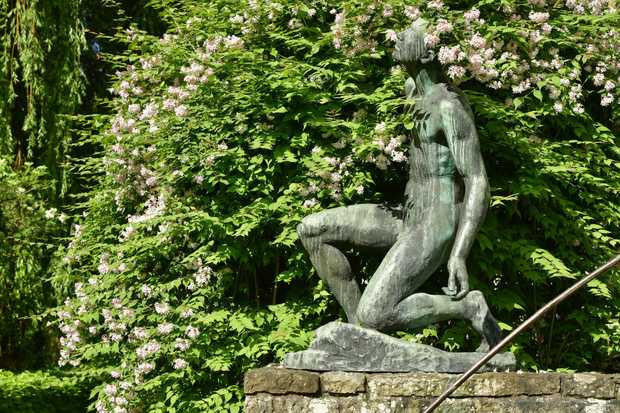Skulptur eines knienden Mannes der nach oben blickt